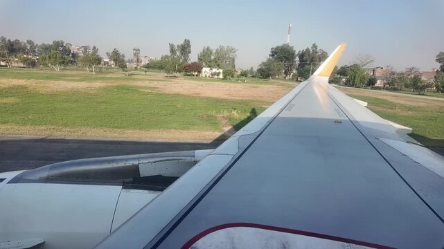 Airplane wing view overlooking Peshawar Airport during flight.