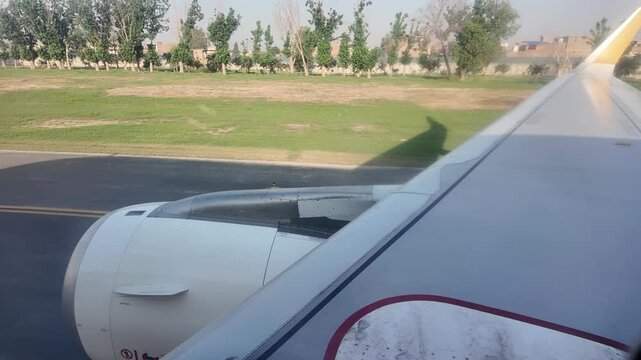 Airplane wing view overlooking Peshawar Airport during flight.