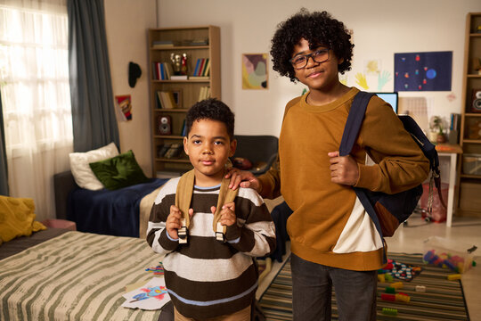 Portrait of Black schoolboy and teenager posing with backpacks, preparing for school at home. Education concept for back to school campaigns, family learning support, medium shot
