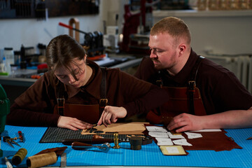 Fototapeta premium Collaborative workshop with leatherworkers cutting patterns on leather.