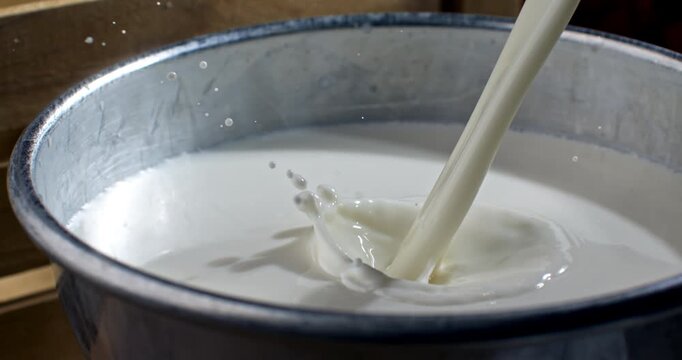 Slow Motion Macro Of Milk Pouring Into Bowl Creating Splash Patterns. Concept Of Nutrition And Fresh Dairy
