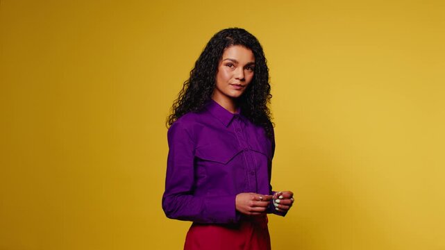 Confident model poses against yellow backdrop, wearing a vibrant purple shirt and red pants, exuding style and personality in a studio shoot.