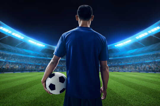 Professional soccer player holding a ball in the stadium field with night lighting