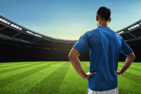 Back view of professional soccer standing in empty stadium field
