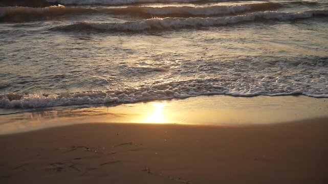 Calm sea waves gently washing over a sandy beach with the sun reflecting on the water surface, fa01