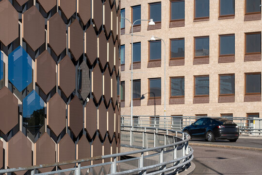 Patterned facade panels border a curving road in Stockholm Sweden, where architecture, urban traffic and geometric street detail converge