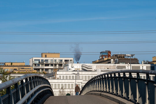 A bridge curve in Oslo near the waterfront, with railings guiding urban infrastructure toward buildings under sky and distant smoke