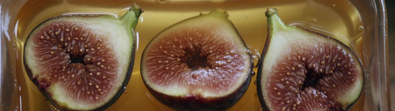 Sweet, ripe figs sliced in half, submerged in clear golden syrup, presenting a nutritious and tasty fruit.