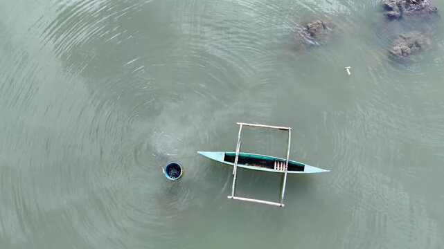 Fisherman diving into ocean waters near traditional wooden outrigger boat while harvesting fresh catch.