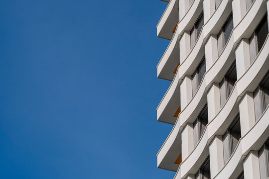 Against blue sky, white balconies define a Lyon France apartment building facade with clean residential architecture and urban rhythm