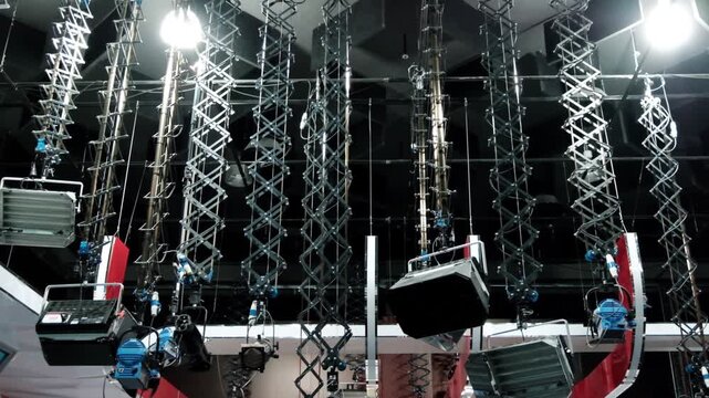 Low angle view of automated studio lighting rig moving down from ceiling in production stage.