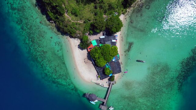Komodo Island bustling tropical beach with many people enjoying the clear blue water. Amazing aerial view vertical bird's eye view drone
