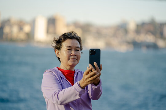 Close Up Senior Asian woman photographing Selfie Sydney Harbour Bridge with smartphone during morning walk, Sydney, Australia. Apr 29,2026