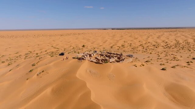 Aerial drone shot of the historic Tisavar Fort ruins surrounded by the golden sands of the Sahara leading toward the Ksar Ghilane Oasis in Tunisia