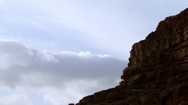 Sunrise timelapse of the majestic Wadi Rum desert in Jordan. Clouds moving over rugged sandstone mountains and red desert landscape. Dramatic morning light in the Valley of the Moon UNESCO site