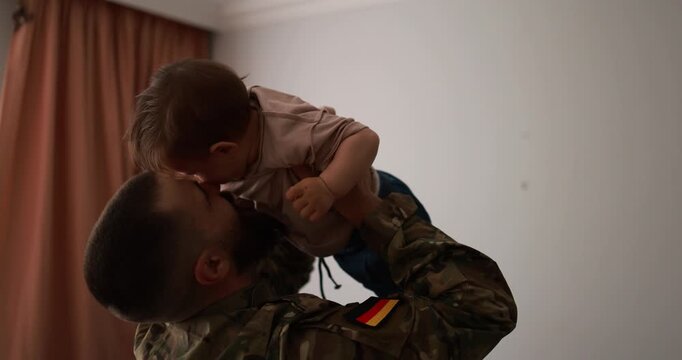 Male german soldier in military uniform hugs his little son at home - Emotional military happy homecoming concept