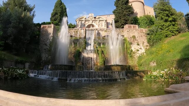 Slow frontal traveling shot toward Neptune Fountain at Villa d'Este, Tivoli. Multi-tiered cascades, lush greenery, and Renaissance facade.