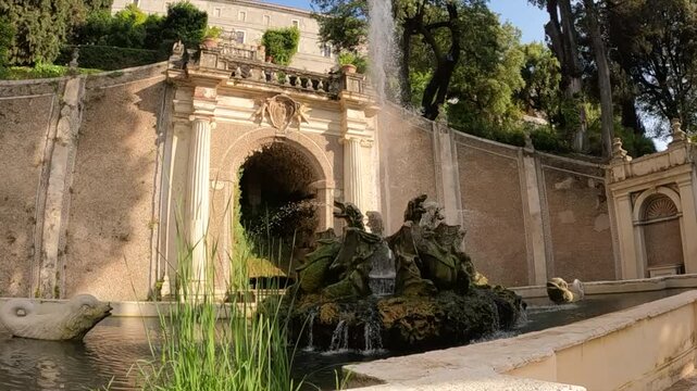 Villa d'Este baroque fountain with sculpted figures, water cascading, ornate stone archway, and lush greenery.