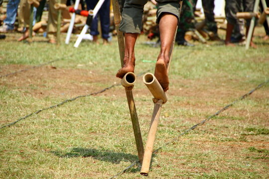 Close up of traditional Indonesian egrang bamboo stilts used during an outdoor cultural game on a grassy field.