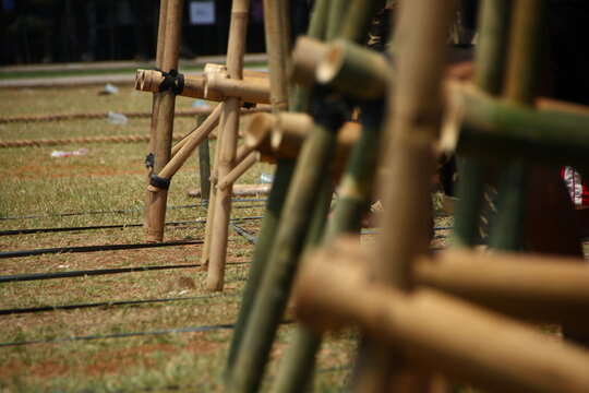 Bare feet balance on bamboo egrang stilts during a traditional Indonesian outdoor competition on a grassy field.