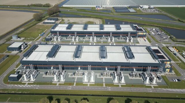 Drone shot of a large hyperscale data center campus with modern industrial architecture, cooling infrastructure and surrounding Dutch landscape in the Netherlands.