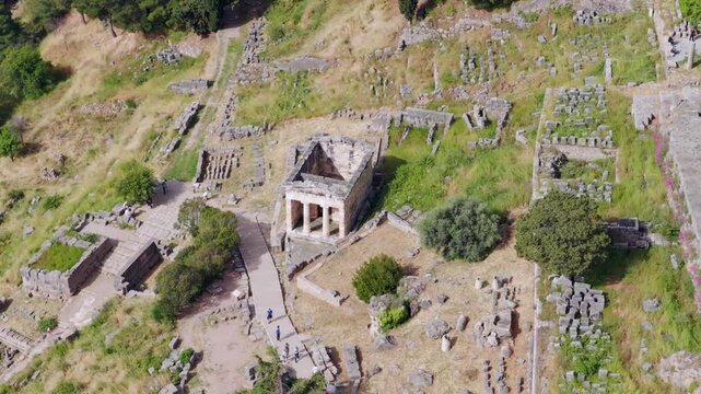 Majestic aerial orbit around the athenian treasury at Delphi, showcasing ancient doric stone ruins within the sanctuary of Apollo, set against mountainous greek landscape