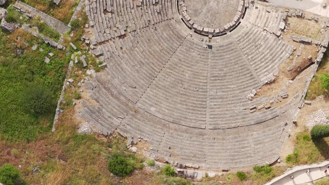 Stunning aerial top-down view of the ancient theater at the archaeological site of Delphi, Greece, showcasing the semicircular stone seating, orchestra, and surrounding historic ruins