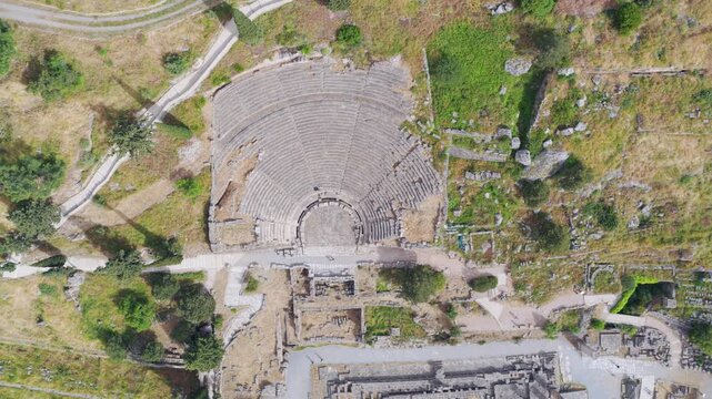 Majestic aerial top-down perspective of the ancient greek theatre of Delphi. Showing the stone structure. Orchestra. And seating area nestled among the surrounding archaeological ruins and landscape