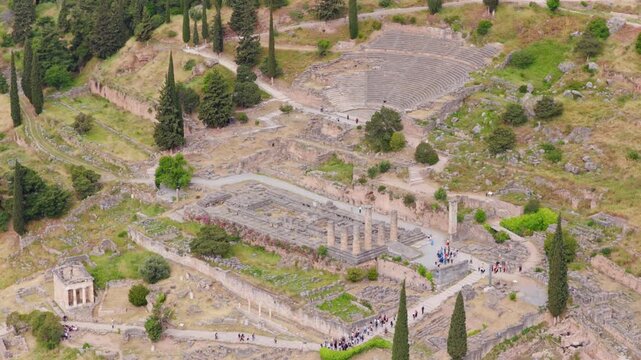Tourists exploring the ancient ruins of the temple of apollo and the amphitheater at the archaeological site of Delphi. Greece. A famous unesco world heritage landmark and popular travel destination
