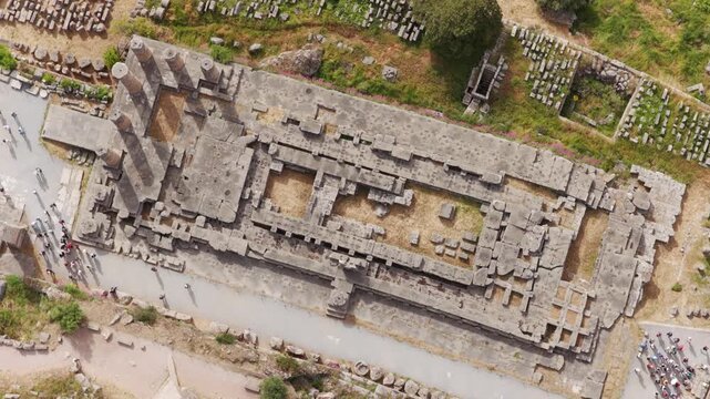 Aerial top-down view of the famous archaeological site of Delphi in Greece, a Unesco world heritage site, with many tourists walking among the ancient ruins of the temple of Apollo