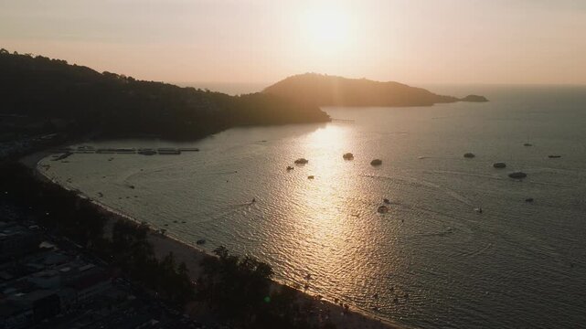 Drone over Phuket bay with parasailing boats and sunset reflection