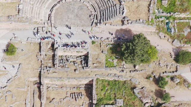 Amazing aerial perspective flying over the magnificent ruins of the ancient theatre of Delphi, a famous archaeological site and a popular tourist destination in Greece on a sunny summer day