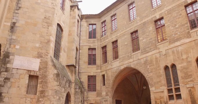 Inner courtyard panning shot of the medieval and neoclassical Palace of the Archbishops of Narbonne by ancient stone walls and arched architecture, South of France