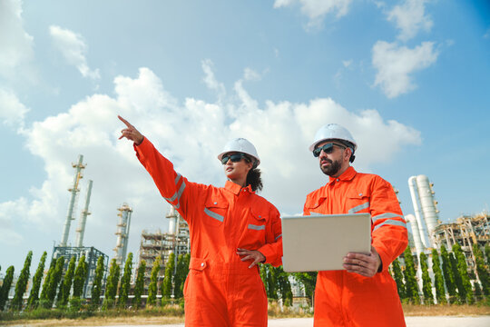 Oil and gas refinery in petroleum industry with inspection engineer, industrial engineer team in orange suit at factory site