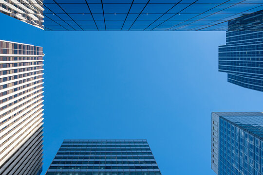 A blue sky void cuts between skyscraper towers in La Defense Paris France, where glass architecture defines the urban business district