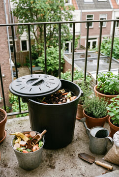 Compost bin and recycling bucket on small balcony with plants .generative AI