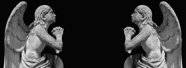 Fototapeta premium Two praying angel statues facing each other in darkness, symbolic image of faith, eternal connection and spiritual dialogue