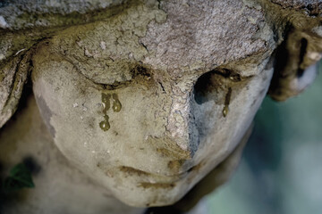 Fototapeta premium Close up of crying angel statue with weathered face and tear stains, symbolic image of sorrow, grief and eternal mourning