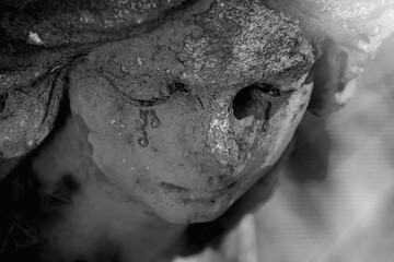 Fototapeta premium Mourning angel statue with dark tears on weathered face, symbolic image of grief, sorrow and eternal sadness
