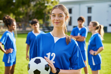 Fototapeta premium Portrait of focused soccer female player holding football ball