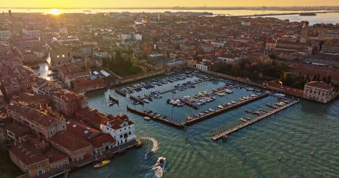 Stunning aerial view of venice at golden hour with boats moving through historic waterways and marina.