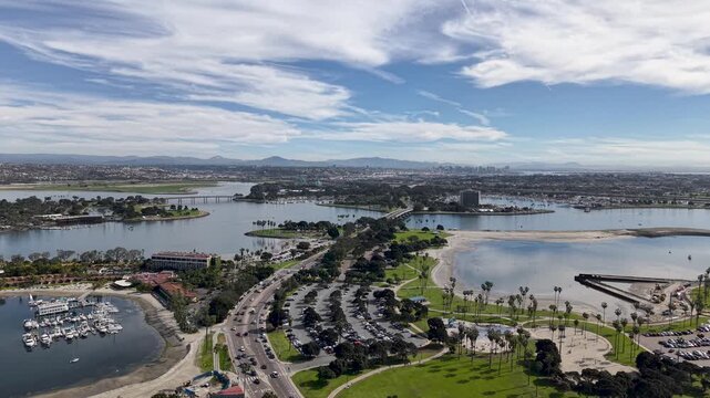 Pacific Beach marina and parking area viewed from directly above, rows of boats at dock and vehicle parking beside the bay waterway, San Diego California.