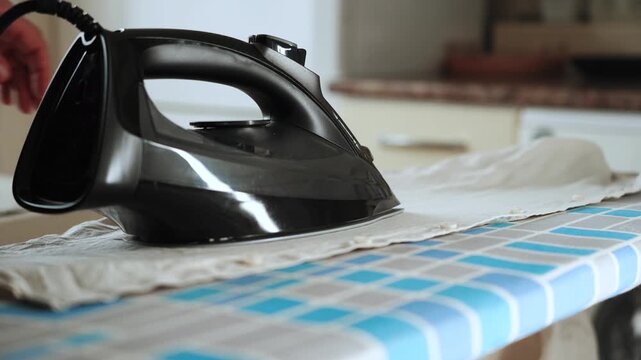 Person irons a white shirt using a black steam iron on a patterned board