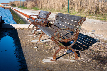 Due panchine di legno e ghisa arrugginita lungo la laguna di Venezia a Pellestrina © Andrea Vismara