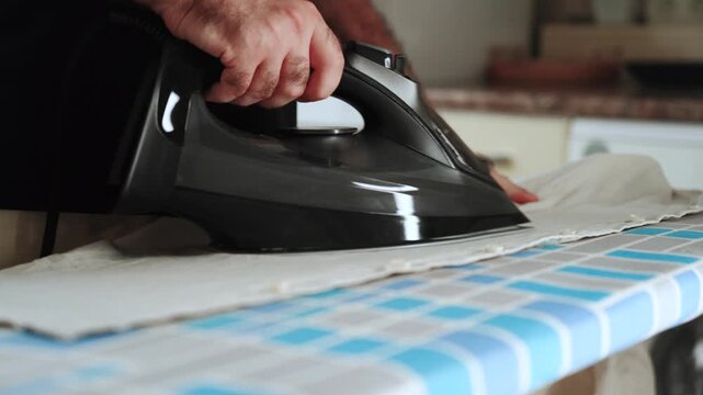 Person ironing clothes on an ironing board at home in the daytime