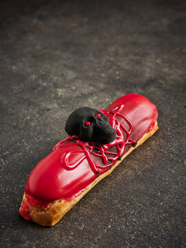 This image features a red dessert eclair topped with a skull decoration and drizzled with black icing. It is ideal for Halloween-themed menus, party promotions, and seasonal marketing campaigns