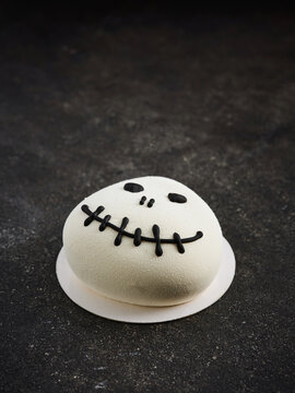 A playful pumpkin-shaped dessert topped with a smiling face made from icing. Ideal for Halloween parties, children's events, or seasonal dessert menus
