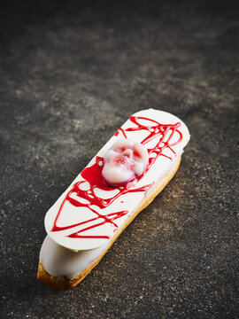 This dessert features an eclair topped with a skull and drizzled with red sauce, perfect for Halloween events
