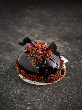 A chocolate dessert dome topped with chocolate crumbs and decorative elements. It is ideal for use in fine dining menus, dessert advertising, or high-end bakery promotions