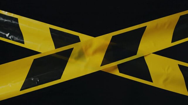 Warning tape cross marking danger zone against a matte black background, safety hazard alert